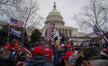 "Rioters outside the US Capitol building holding 'Make America Great Again' flags" by Tyler Member