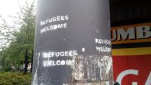 Graffiti placed by a vandal on a pole stating that refugees are welcome in the city of Groningen.