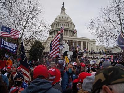 "Rioters outside the US Capitol building holding 'Make America Great Again' flags" by Tyler Member