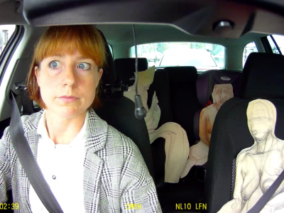 A woman sits in a car with cutout figures in the other seats. Image credit: Shona Macnaughton - Here to Deliver.
