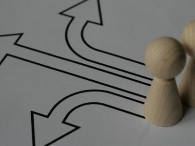 Two small wooden game tokens with arrows pointing away from them in different directions